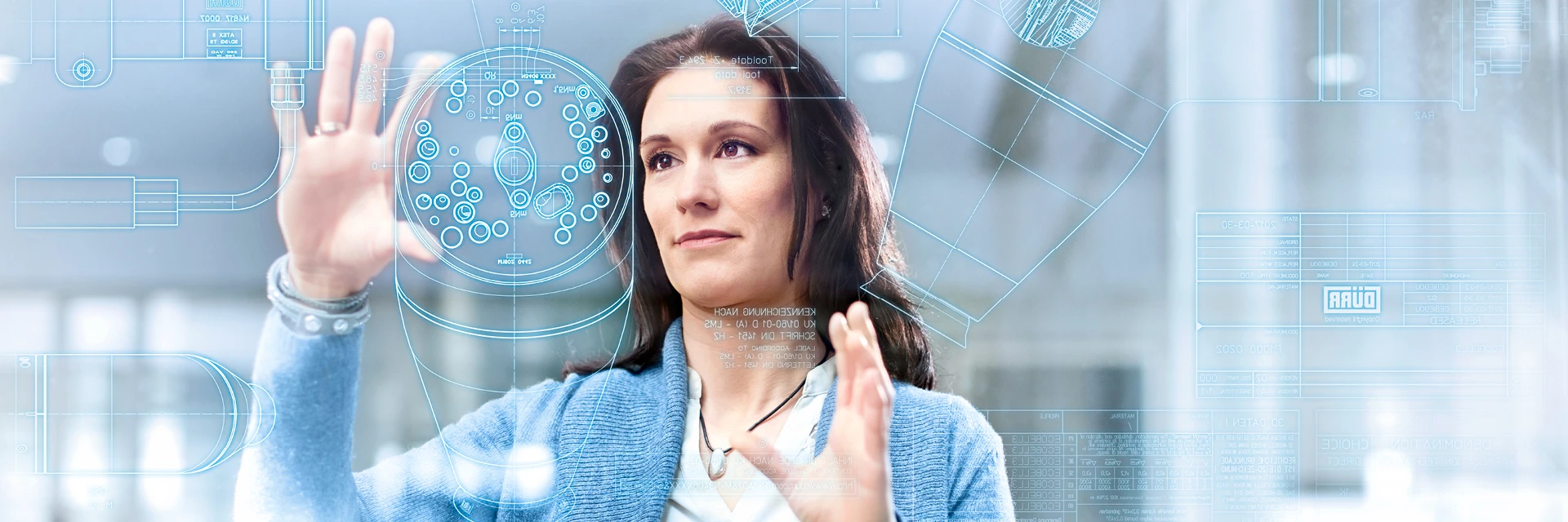 Person interagiert mit einem transparenten Touchscreen, der technische Konstruktionszeichnungen und digitale Interface-Elemente anzeigt.